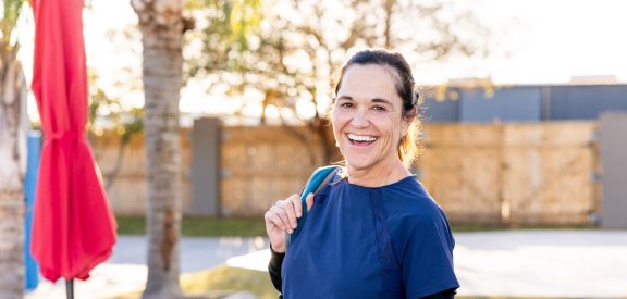 Advanced spine patient smiling at camera holding pickleball equipment