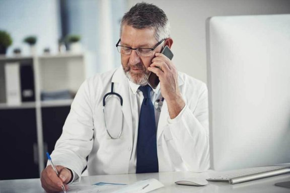 Male doctor talking on the phone and taking notes