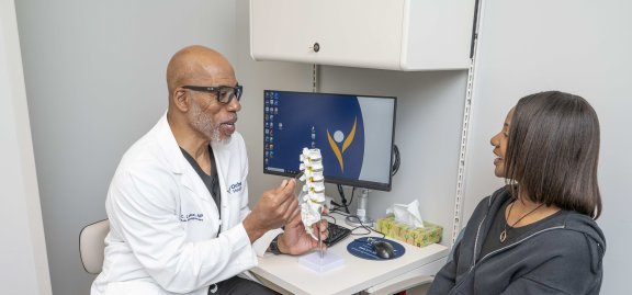 Doctor talking to patient showing model of spine