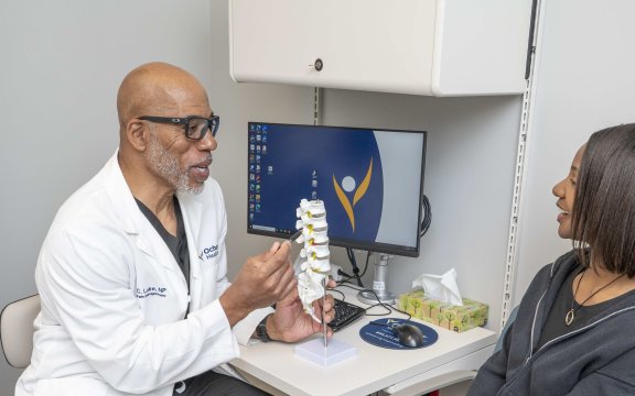 Doctor talking to patient showing model of spine
