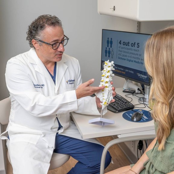 Doctor showing patient model of spine in office