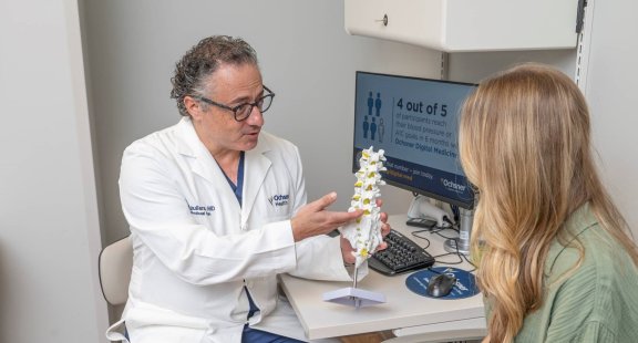 Doctor showing patient model of spine in office