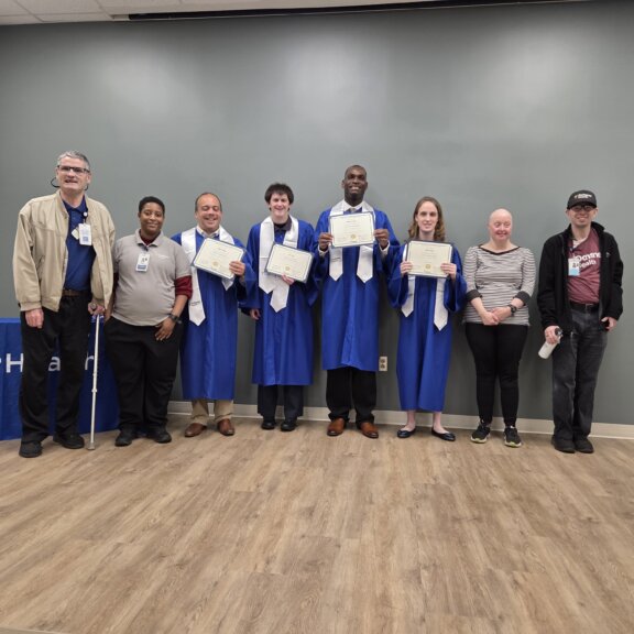 STEP 2 Adult students in regalia holding diplomas