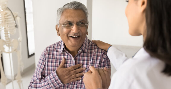 Young doctor talking to older patient sitting down