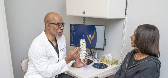 Doctor talking to patient showing model of spine