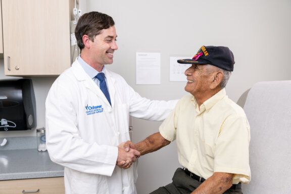 Vascular Surgeon shaking hands with aortic patient in patient room.