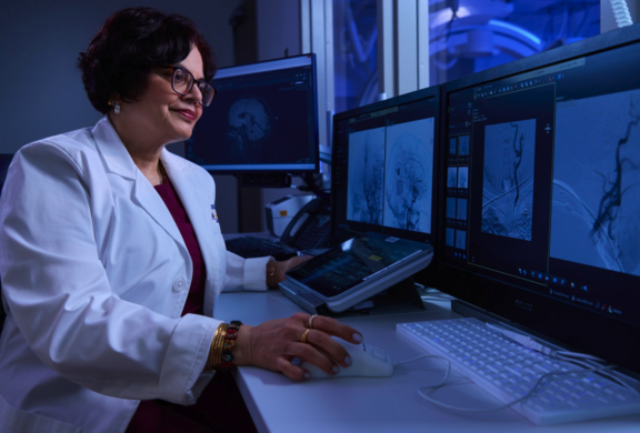 Person in a lab coat at computer review radiology image