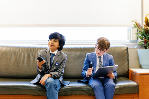 Kids' Council members sitting on a couch in a hospital lounge taking notes and holding a remote