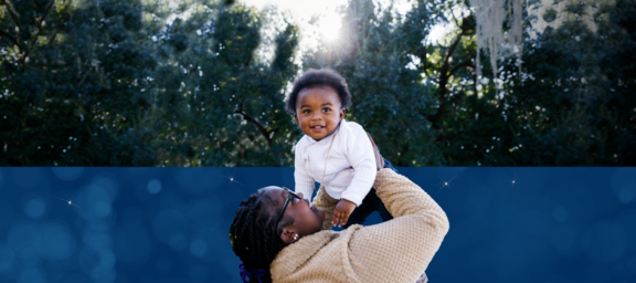 Woman holding child up in the air while child smiles