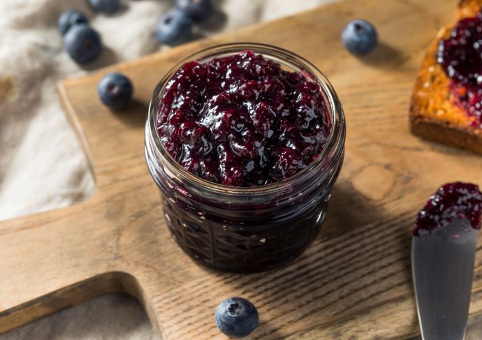 Jar of homemade berry jam on a wood chopping board