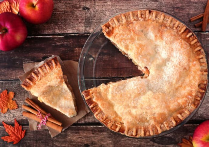 An apple pie displayed on a table with a slice cut out