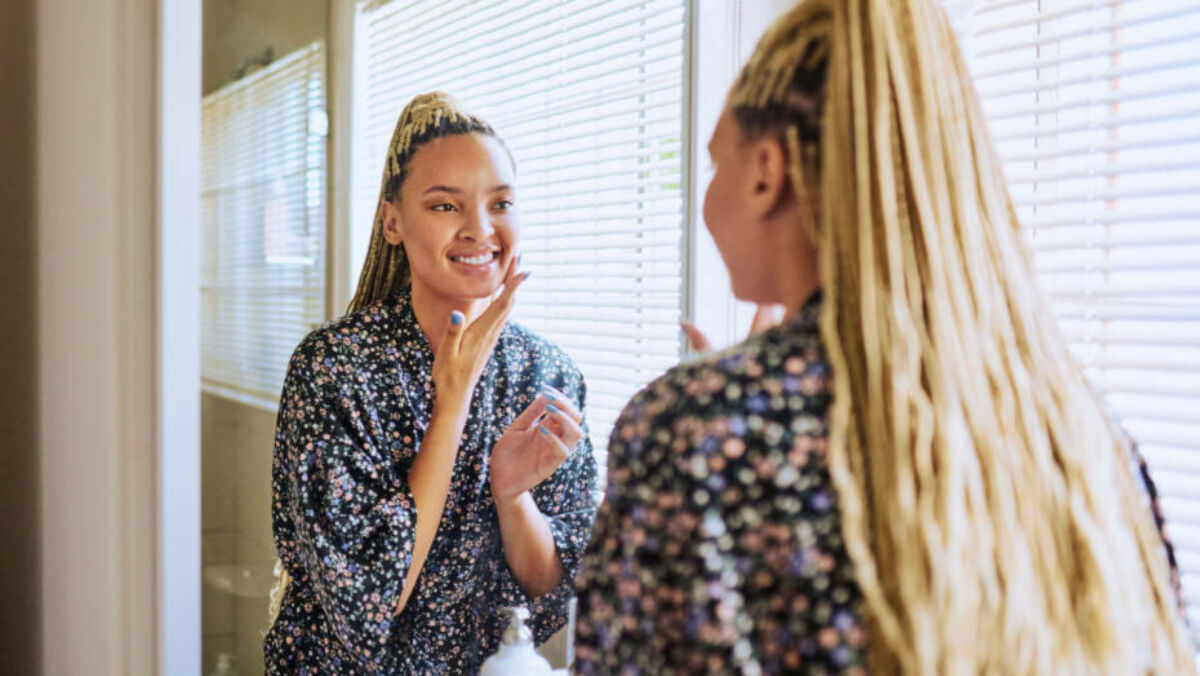 Woman looking in mirror and taking care of her skin