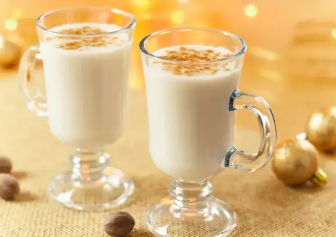 Two glasses filled with eggnog on a holiday table setting