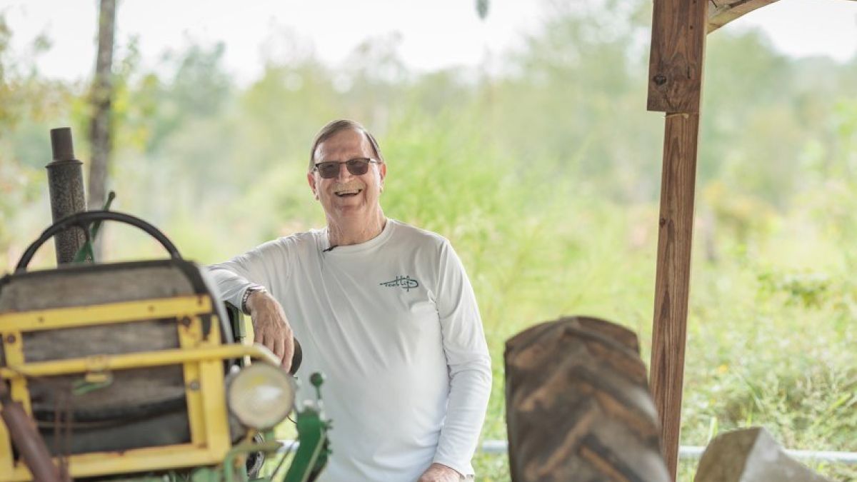 Cancer care patient leaning against a tractor
