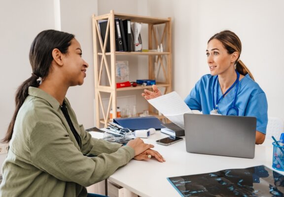 Woman patient speaking with doctor behind desk