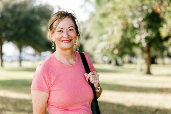 Neuroscience patient Alicia outside holding yoga equipment