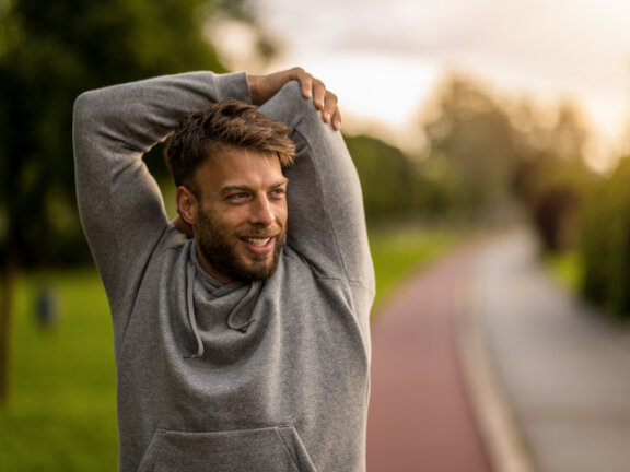 Man outside stretching and smiling