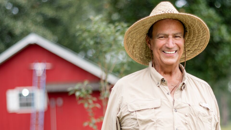 Heart failure and LVAD patient, Dale, standing outside on his farm smiling