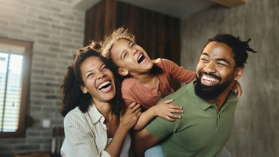Child riding piggy back on dad with mom laughing