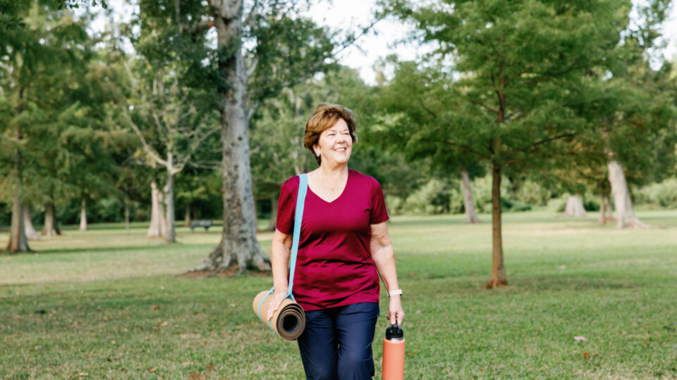 Woman walking in the park with yoga mat and water bottle