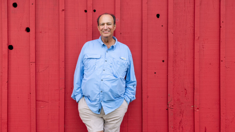 Heart failure patient smiling and leaning against a red barn