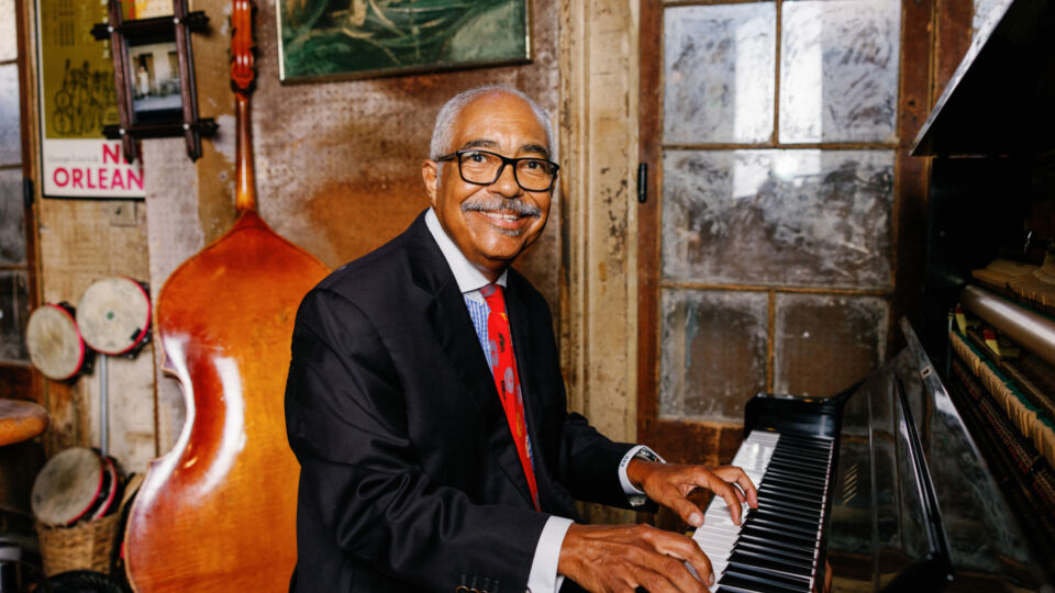 Rickie Monie sitting at a piano smiling