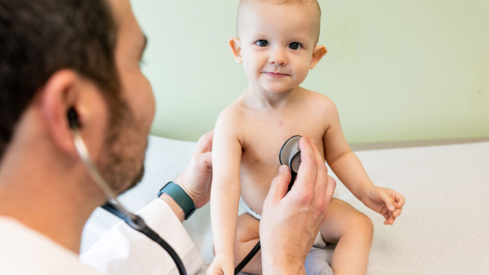 pediatric cardiologist listening to pediatric patient's heart with a stethoscope