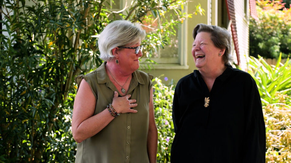 Two women, both lung cancer survivors, standing in garden laughing