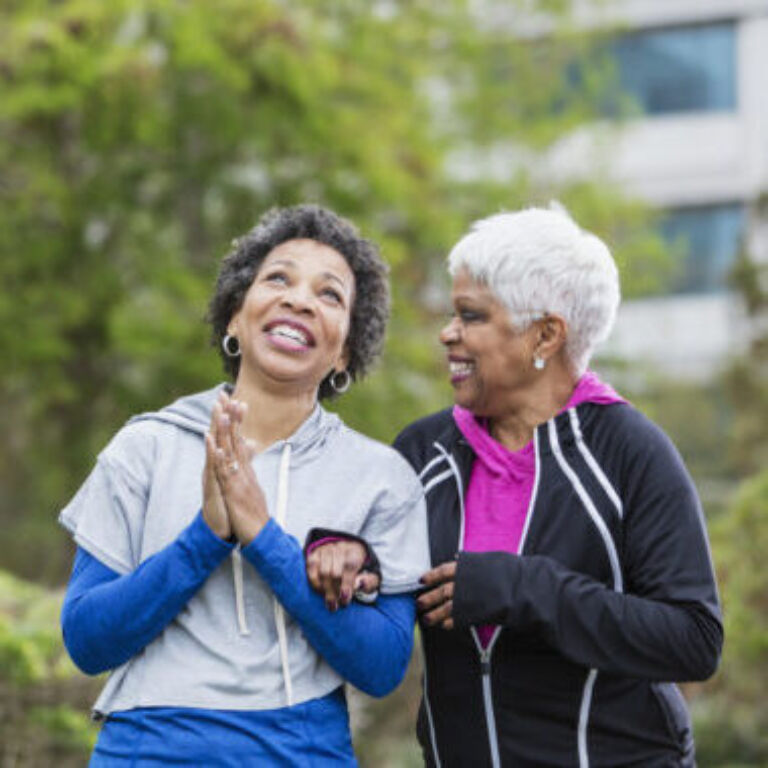 Two mature women walking outside laughing